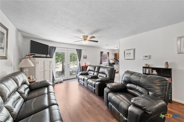 living room featuring hardwood / wood-style floors, ceiling fan, a textured ceiling, and french doors