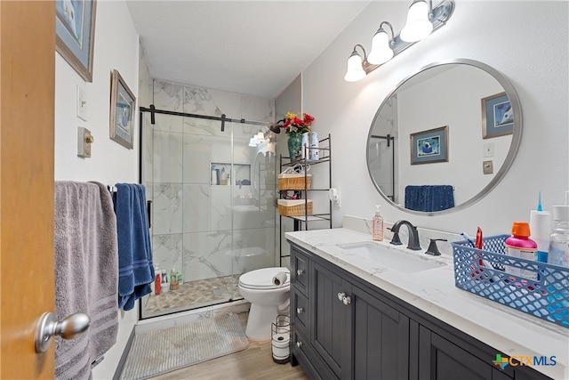 bathroom with hardwood / wood-style flooring, a shower with door, a textured ceiling, vanity, and toilet