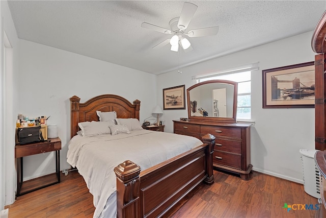 bedroom featuring dark wood-type flooring, ceiling fan, and a textured ceiling