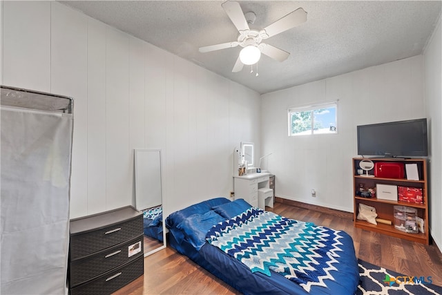 bedroom featuring ceiling fan, a textured ceiling, and dark hardwood / wood-style floors