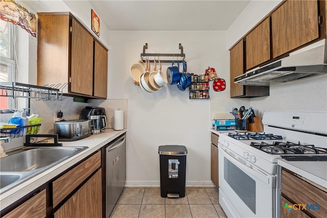 kitchen featuring dishwasher, white gas range, light tile patterned floors, and sink