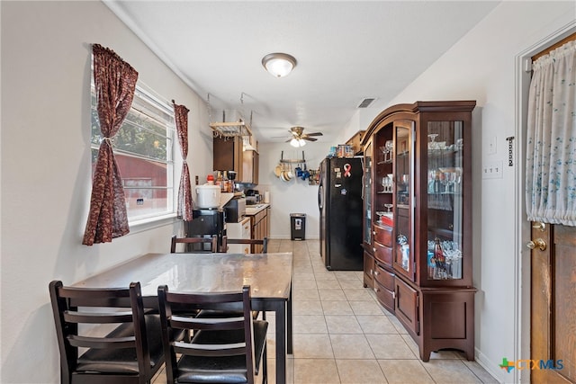 kitchen featuring kitchen peninsula, light tile patterned floors, ceiling fan, and black refrigerator