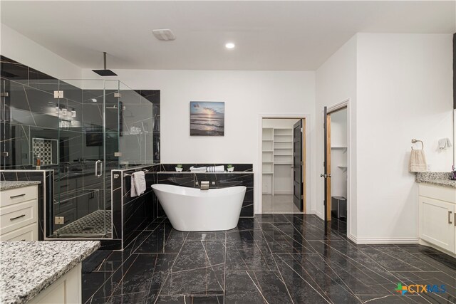 bathroom with vanity, plus walk in shower, and tile walls