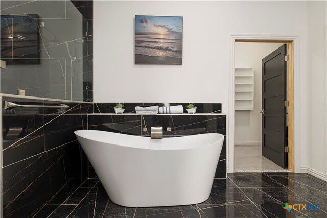 bathroom featuring tile walls and a bath