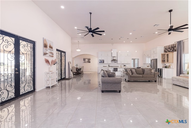 living room with french doors, ceiling fan, and a high ceiling