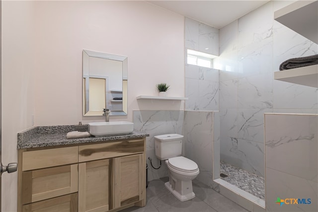 bathroom featuring tile walls, toilet, vanity, and a tile shower