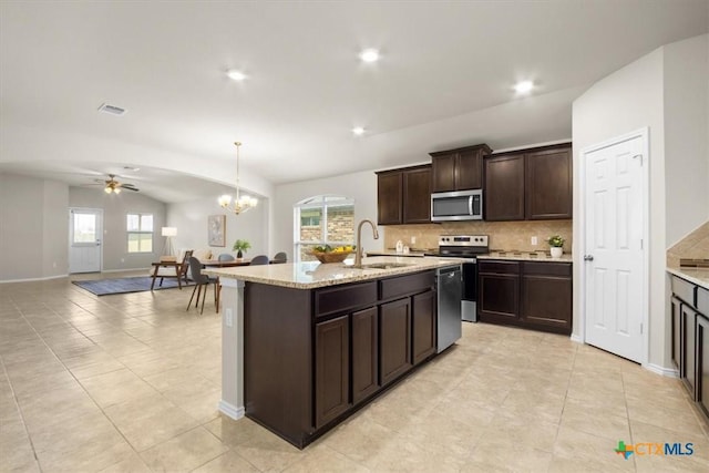 kitchen with sink, an island with sink, stainless steel appliances, and ceiling fan with notable chandelier