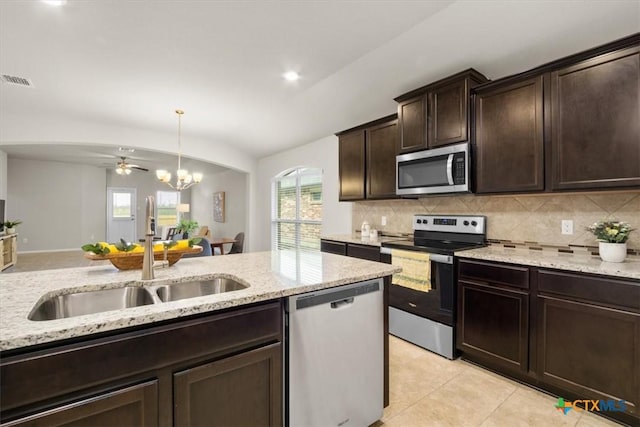 kitchen featuring appliances with stainless steel finishes, backsplash, ceiling fan with notable chandelier, dark brown cabinetry, and sink