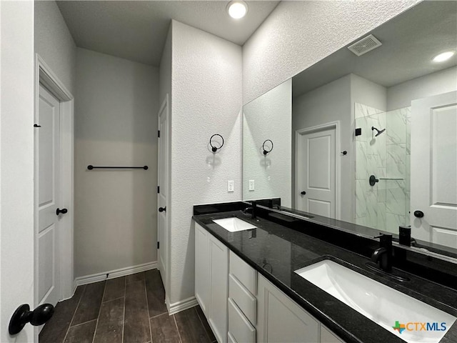 bathroom with vanity and a tile shower