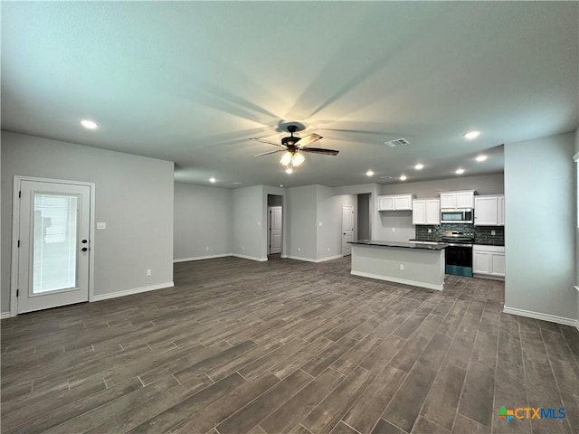 unfurnished living room with ceiling fan and dark wood-type flooring