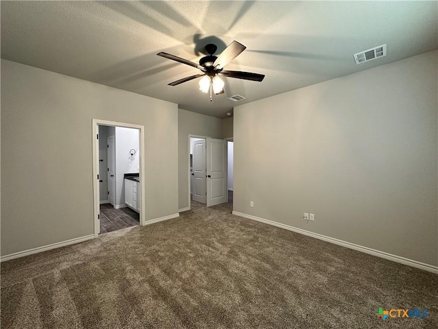 unfurnished bedroom featuring ceiling fan, ensuite bathroom, and dark carpet