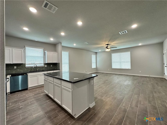 kitchen featuring ceiling fan, sink, a kitchen island, stainless steel dishwasher, and white cabinets