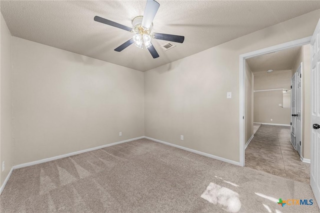 empty room with carpet flooring, a ceiling fan, baseboards, and a textured ceiling