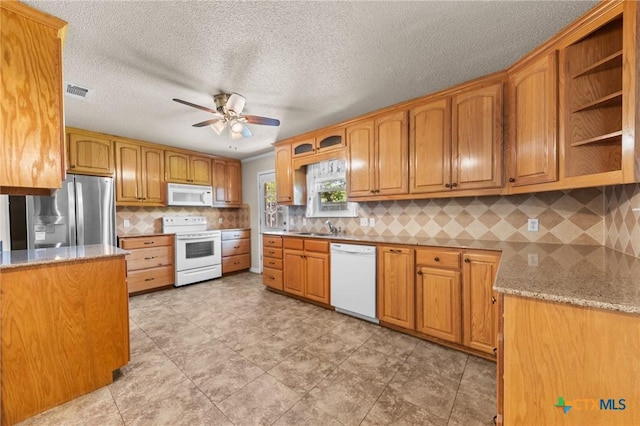 kitchen featuring white appliances, ceiling fan, light stone countertops, backsplash, and a textured ceiling
