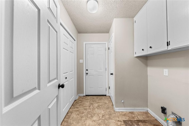 washroom featuring cabinet space, baseboards, and a textured ceiling