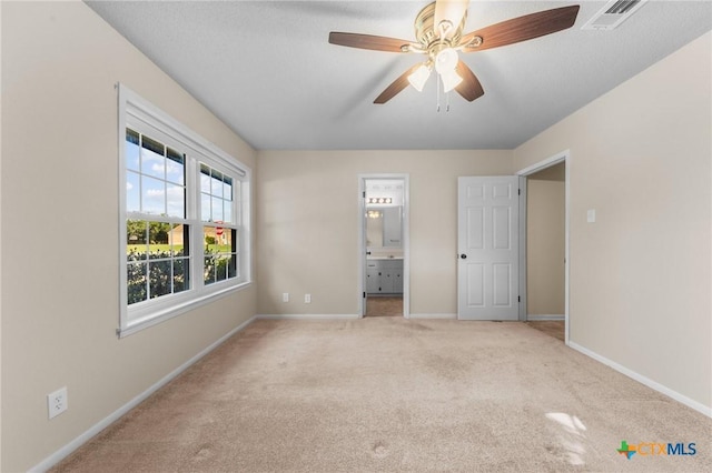 unfurnished bedroom featuring carpet flooring, baseboards, ensuite bath, and a ceiling fan