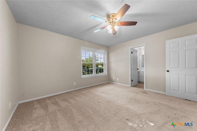unfurnished bedroom featuring carpet flooring, baseboards, a textured ceiling, ensuite bath, and ceiling fan
