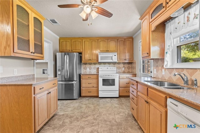 kitchen with white appliances, a sink, ceiling fan, light stone countertops, and crown molding