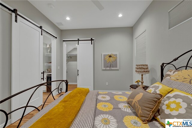 bedroom with light wood-type flooring and a barn door