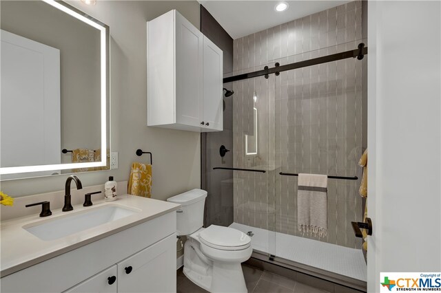 bathroom featuring tile patterned flooring, vanity, toilet, and a shower with door