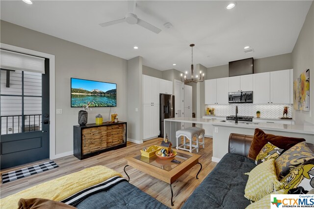 living room featuring light hardwood / wood-style floors and ceiling fan with notable chandelier