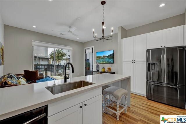 kitchen featuring stainless steel fridge with ice dispenser, pendant lighting, sink, white cabinets, and light hardwood / wood-style flooring