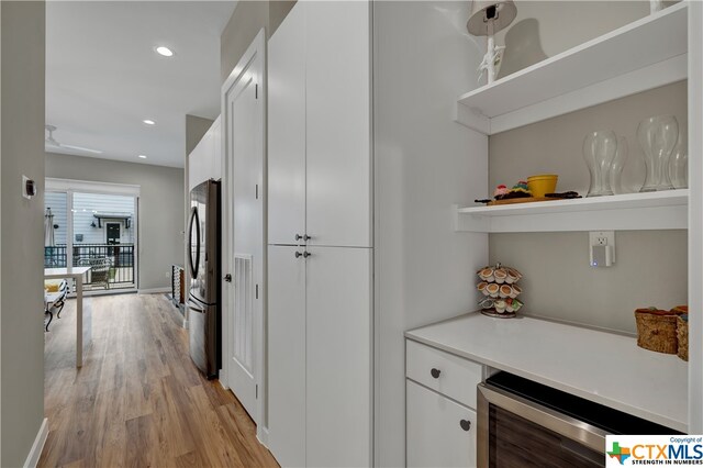 interior space featuring white cabinetry, beverage cooler, stainless steel refrigerator, and light hardwood / wood-style floors