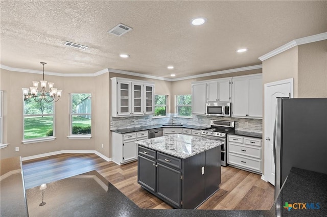 574 Rose Ln, Salado, TX 76571 - kitchen with stainless steel appliances, wood finished floors, a chandelier, white cabinetry, and a textured ceiling