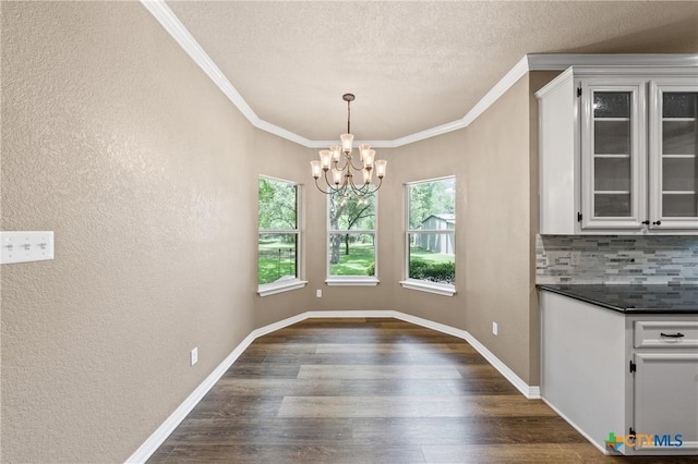 574 Rose Ln, Salado, TX 76571 - unfurnished dining area with healthy amount of natural light, dark wood finished floors, a chandelier, crown molding, and a textured wall