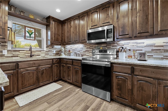 kitchen with stainless steel appliances, light stone countertops, light hardwood / wood-style floors, and tasteful backsplash