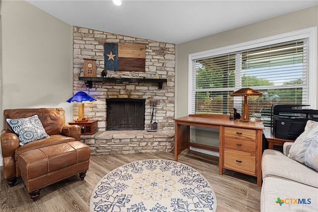 living room with a stone fireplace, light wood-type flooring, and lofted ceiling