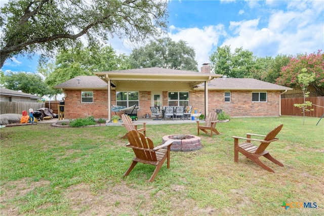 rear view of property featuring a lawn, a patio, and a fire pit