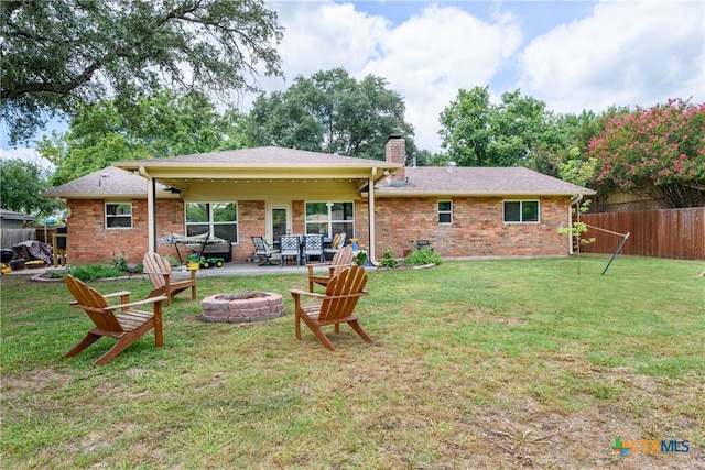 back of property featuring a lawn, an outdoor fire pit, and a patio