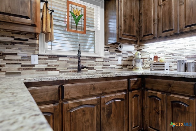 kitchen with tasteful backsplash, light stone countertops, and dark brown cabinets