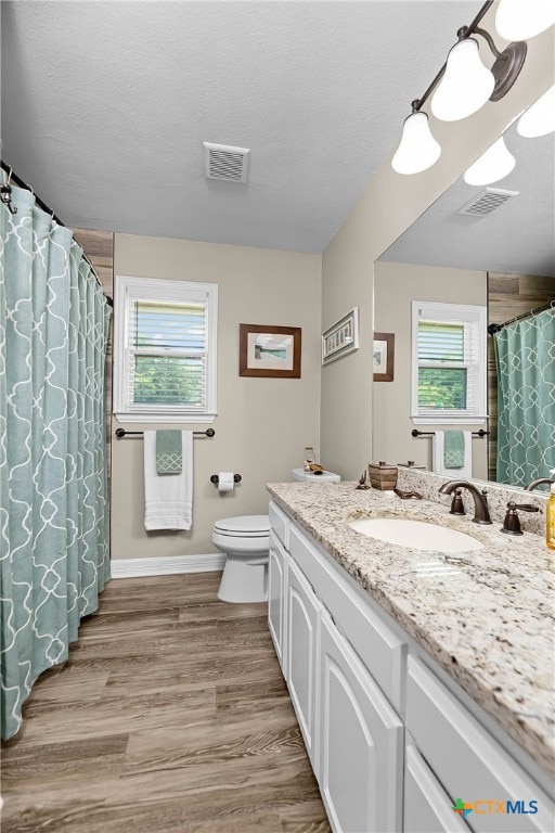 bathroom featuring vanity, hardwood / wood-style flooring, plenty of natural light, and toilet