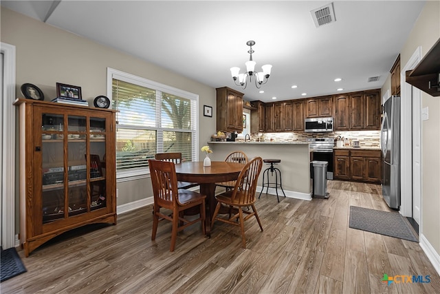 dining area with sink, an inviting chandelier, and hardwood / wood-style flooring