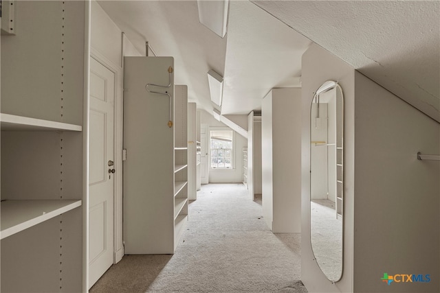 hallway with a textured ceiling and light carpet