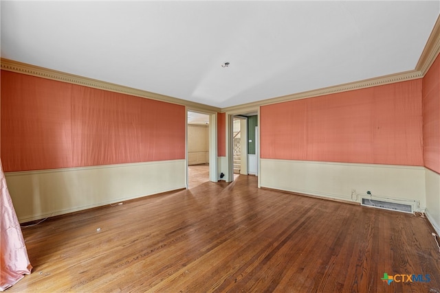 empty room with hardwood / wood-style flooring and crown molding