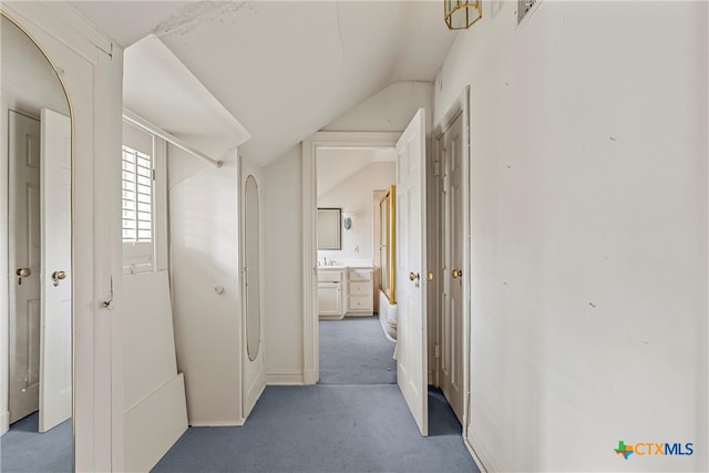 hallway featuring lofted ceiling and carpet