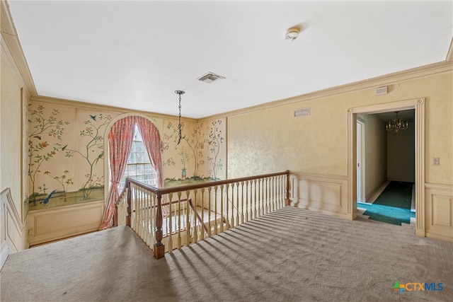 hallway featuring ornamental molding, carpet flooring, and a notable chandelier