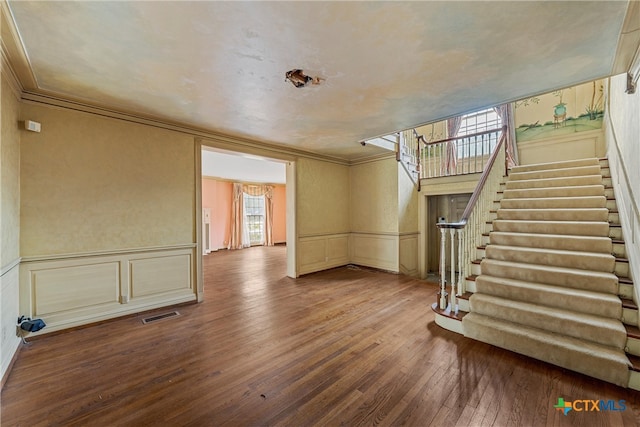 unfurnished living room featuring hardwood / wood-style flooring and crown molding