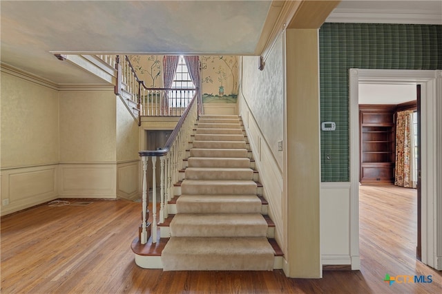 stairs with hardwood / wood-style flooring and crown molding