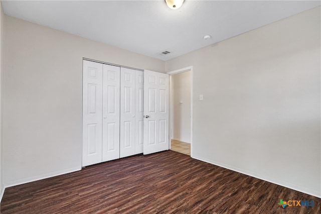 unfurnished bedroom with dark hardwood / wood-style floors and a closet