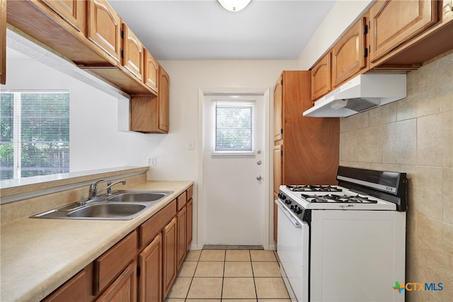 kitchen with sink, white gas stove, backsplash, and light tile patterned floors