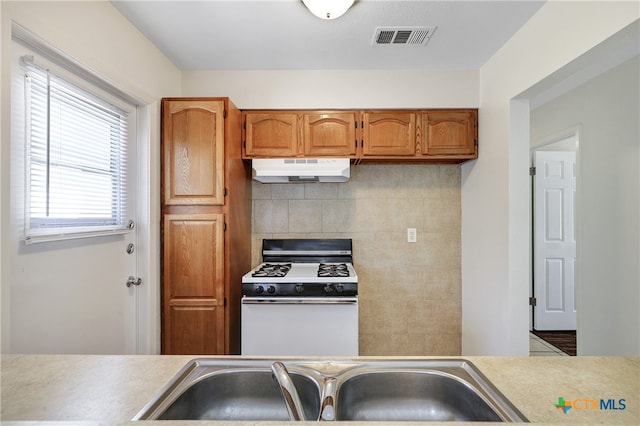 kitchen featuring tasteful backsplash, sink, and white gas range oven