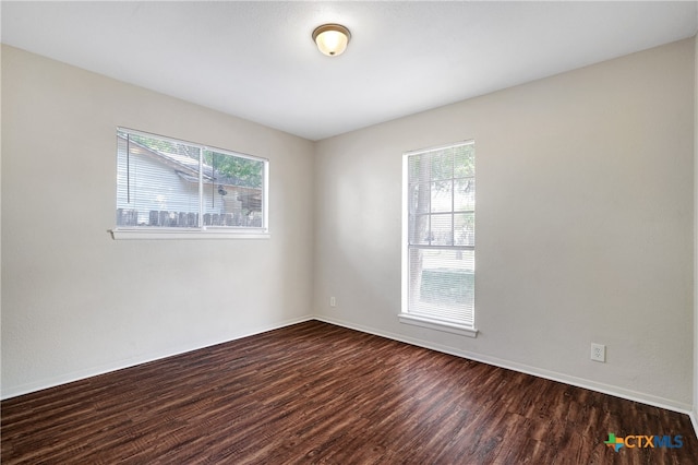 empty room with dark wood-type flooring and plenty of natural light