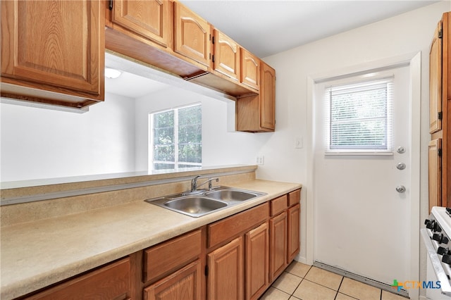 kitchen featuring light tile patterned flooring, a wealth of natural light, sink, and white range with gas stovetop