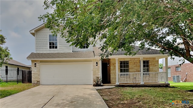 view of front of home with a front lawn, a garage, central AC, and covered porch