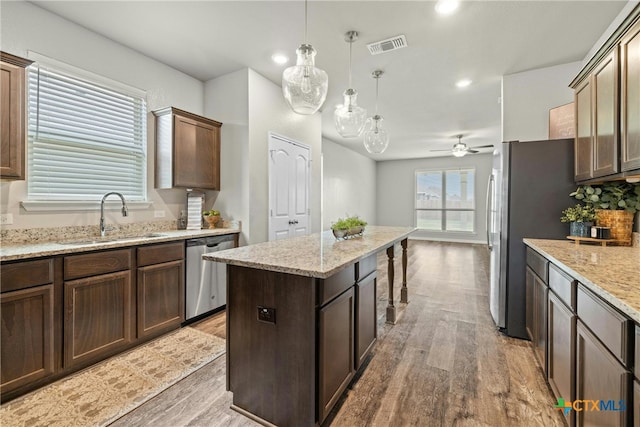 kitchen featuring hanging light fixtures, sink, ceiling fan, appliances with stainless steel finishes, and a kitchen island