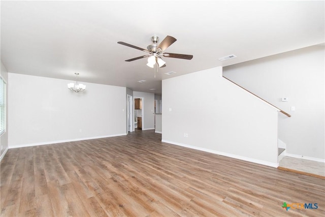 unfurnished living room with ceiling fan with notable chandelier and light hardwood / wood-style floors